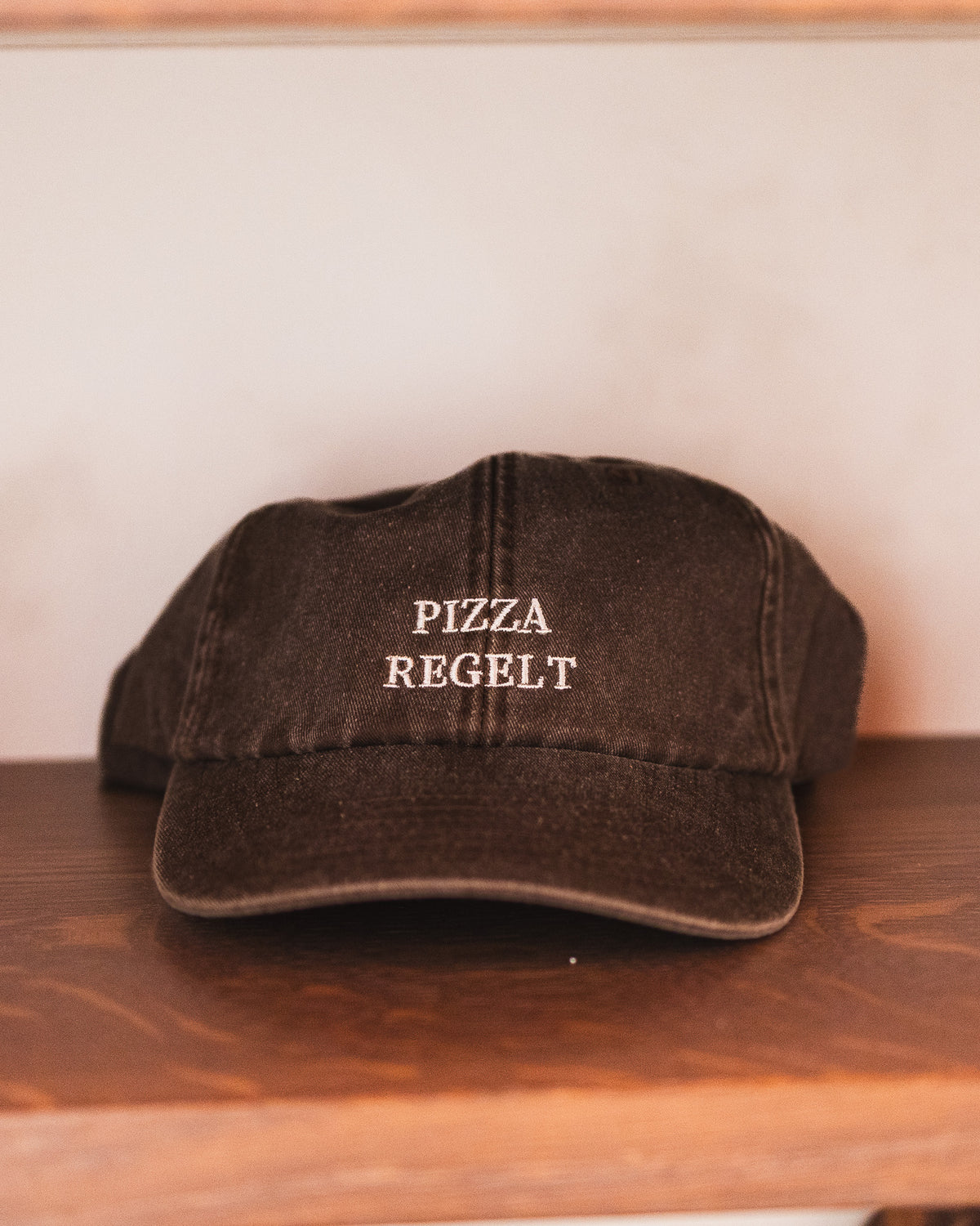 Dunkle Kappe mit dem Spruch „PIZZA REGELT“