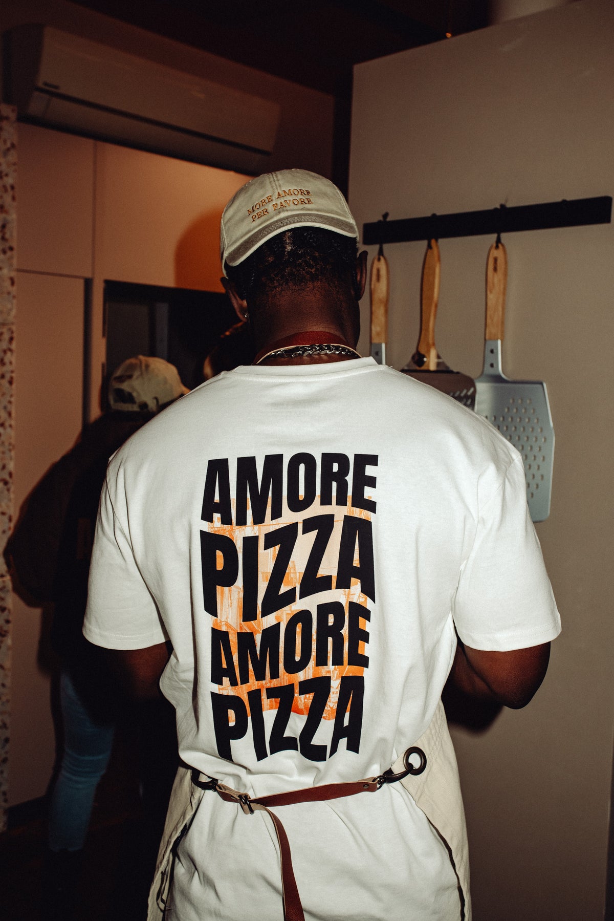 Person trägt das weiße Shirt mit dem Druck „AMORE PIZZA“