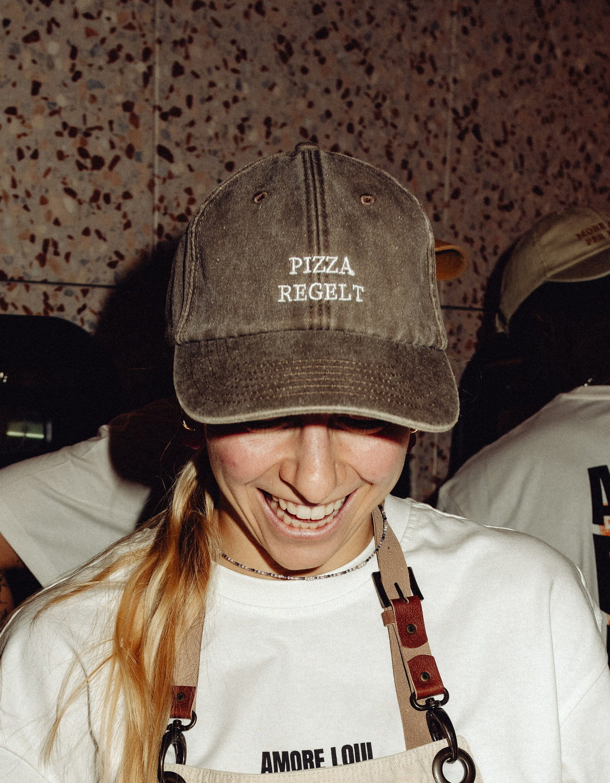 Frau trägt eine Kappe mit dem Spruch „PIZZA REGELT“