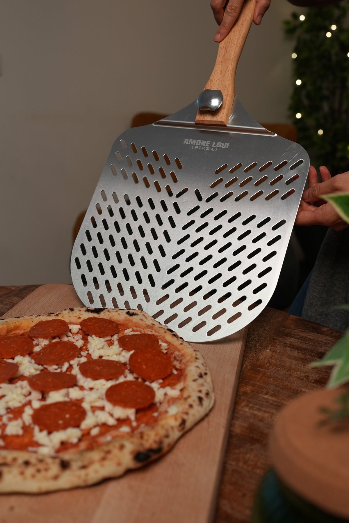 Pizzaschieber wird unter eine belegte Pizza geschoben