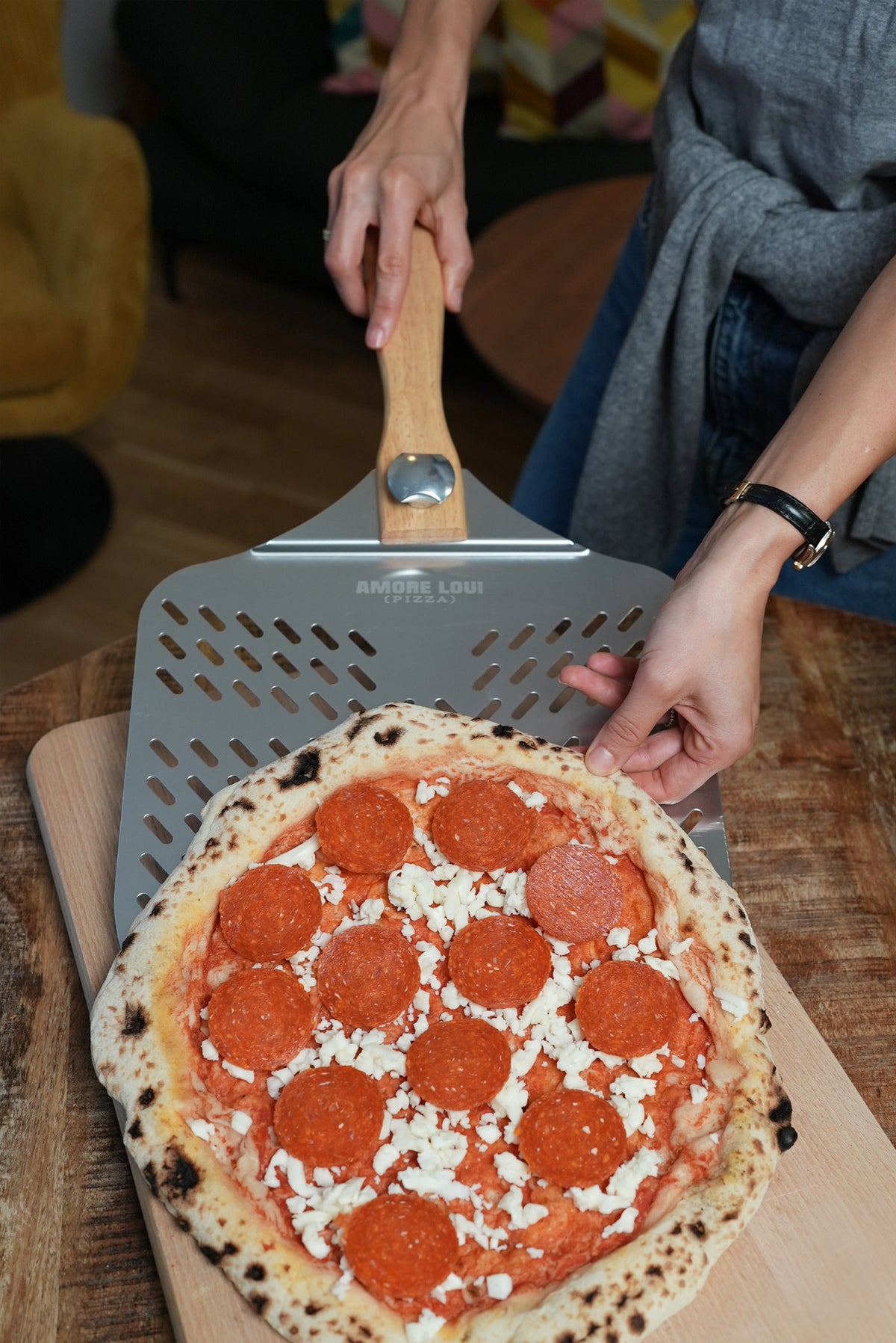 Frau schiebt eine Pizza auf den Pizzaschieber