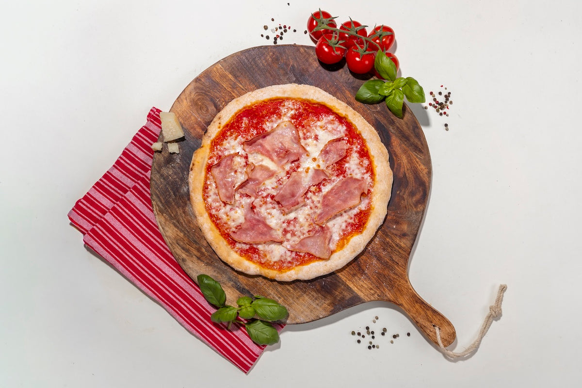 Pizza Cotta glutenfrei auf einem Holzbrett mit Zutaten daneben