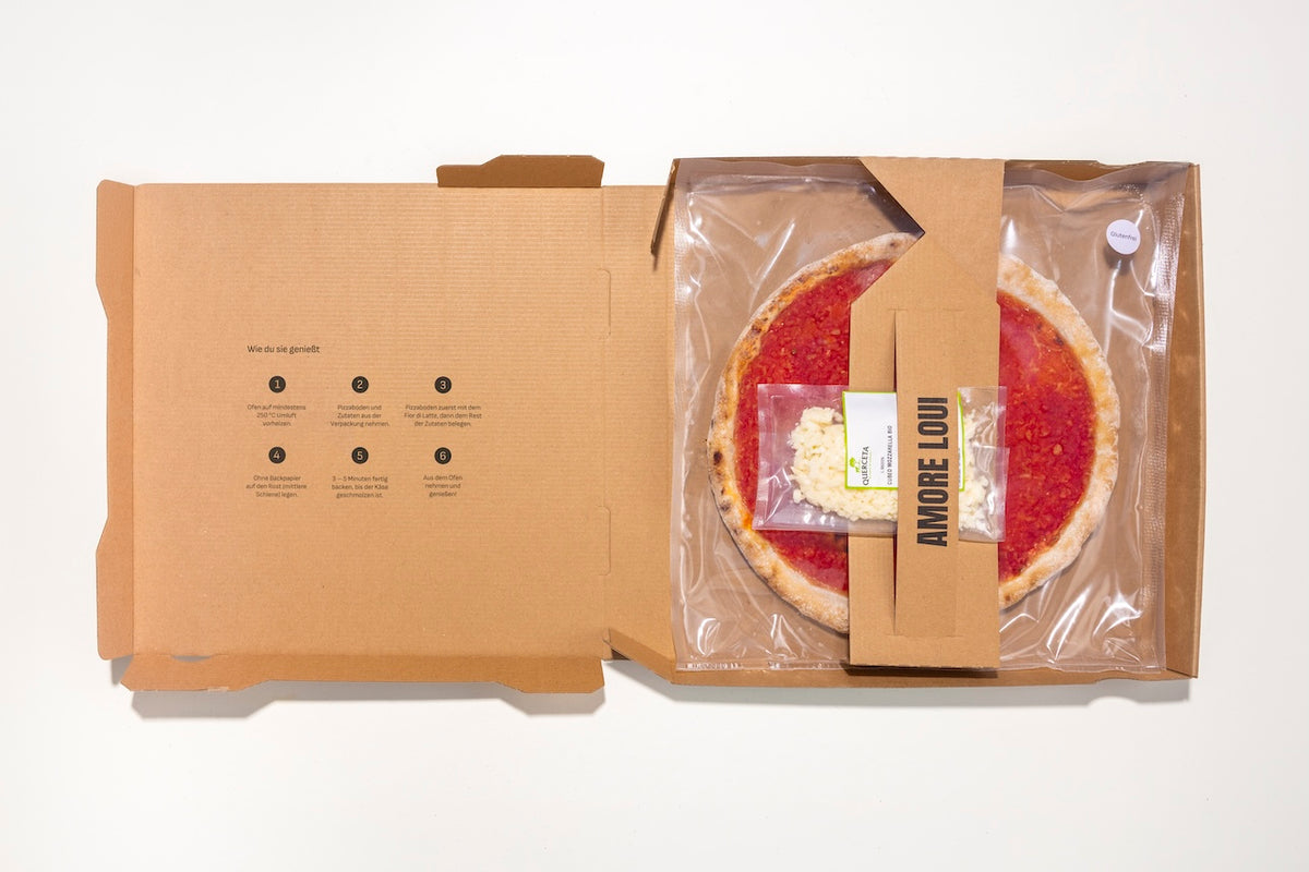 Geöffneter Karton mit glutenfreiem Pizzaboden und separat verpackten Zutaten