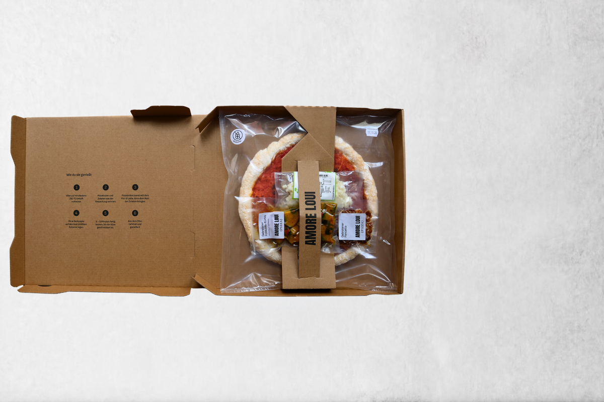 Geöffneter AMORE LOUI Karton mit Pizzaboden und separat verpackten Zutaten