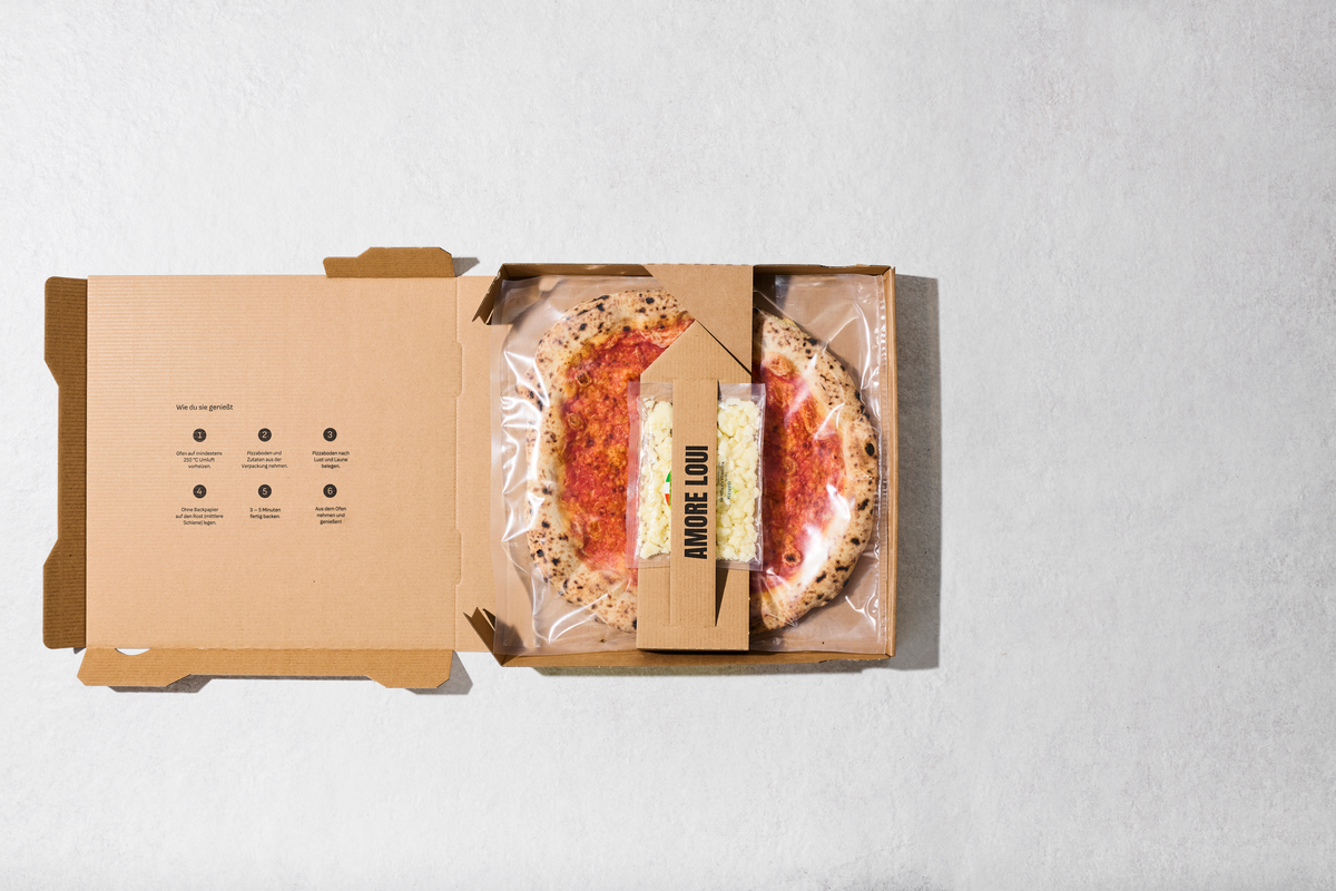 Geöffneter Karton mit Pizzaboden und separat verpackten Zutaten