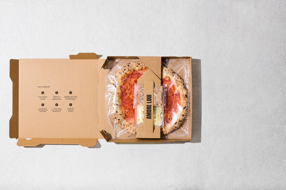 Geöffneter Karton mit Pizzaboden und separat verpackten Zutaten